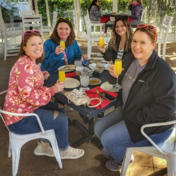 a group of people sitting at a table with mimosas in hand