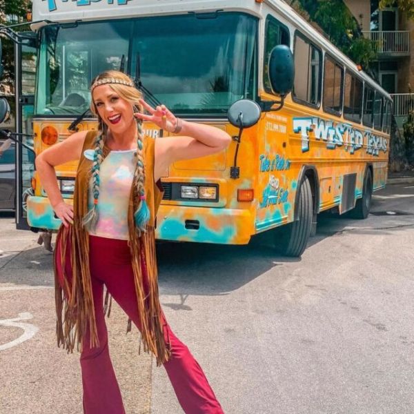 a person dressed like a hippie standing in front of a bus