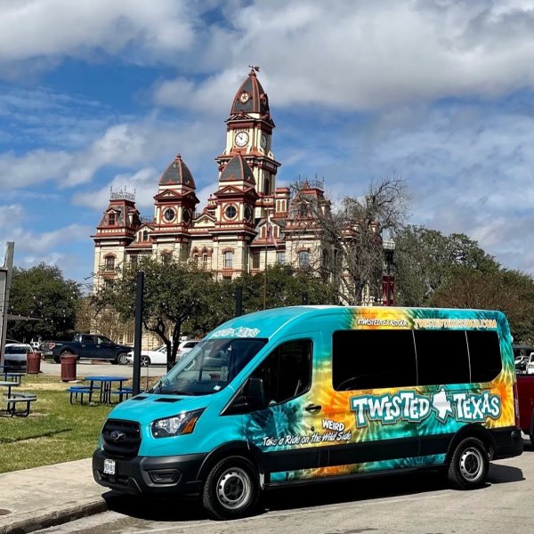 a blue and teal tie dyed van parked in front of city hall