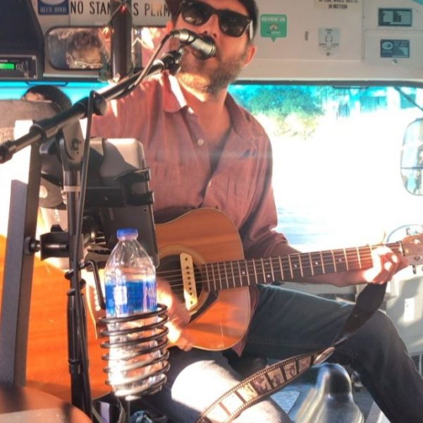 a man holding a guitar and singing into microphone
