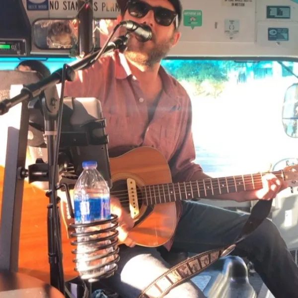 a man holding a guitar and singing into microphone